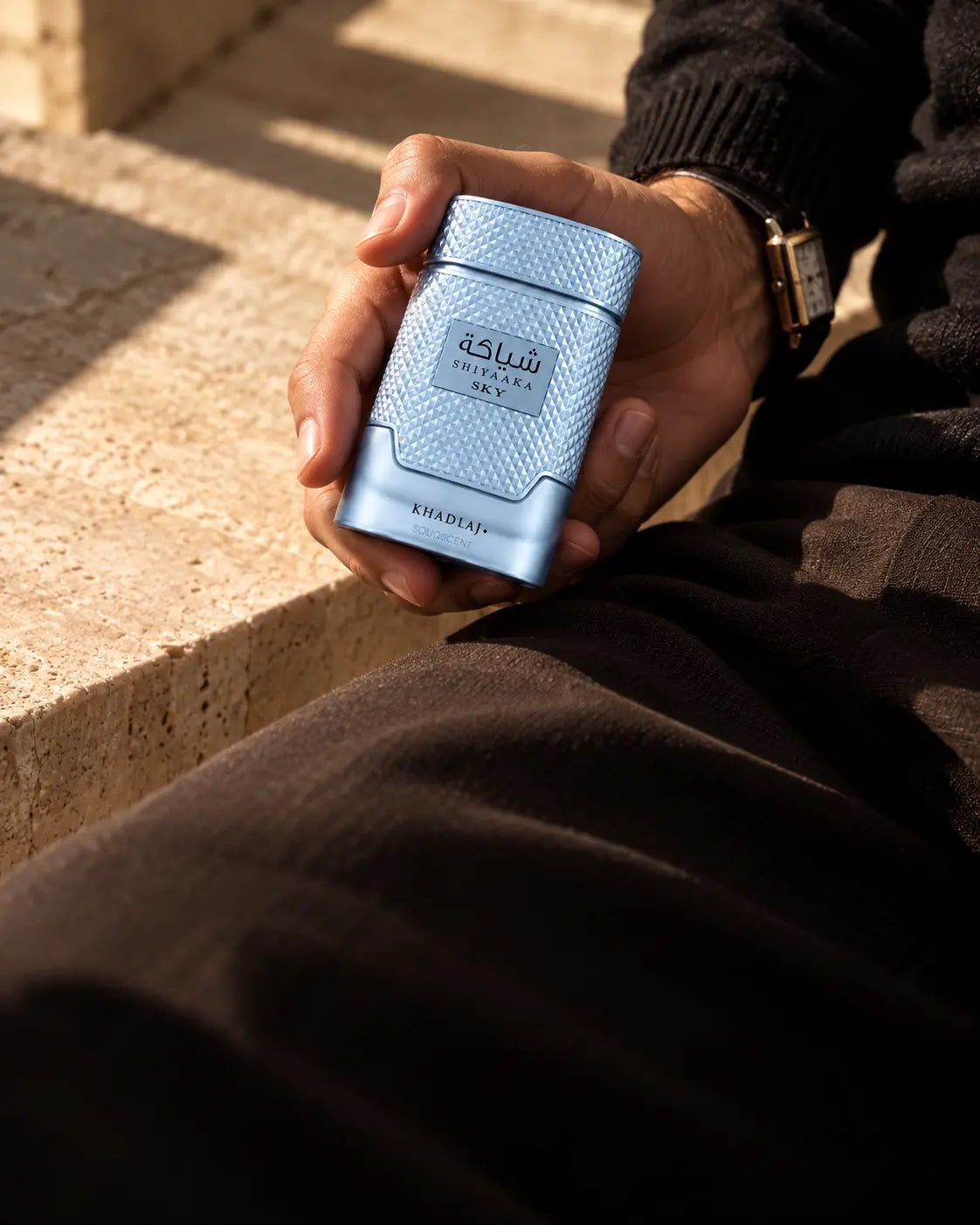 Shiyaaka Sky fragrance held with black tailoring in warm sunlight